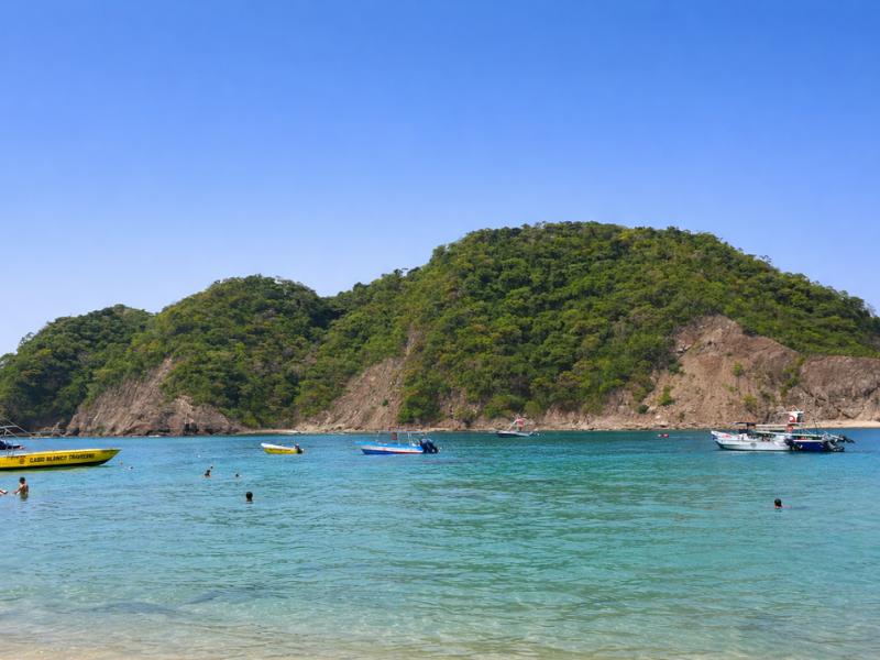 Tour boat anchored off the white sand beach at Isla Tortuga in the Gulf of Nicoya